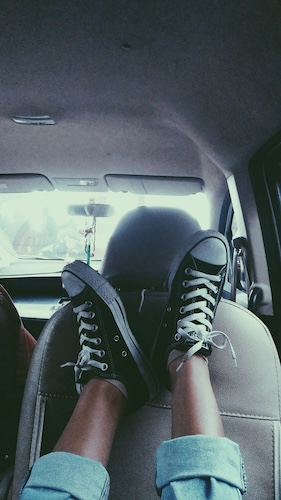feet resting on the back seat of a car during a road trip with kids