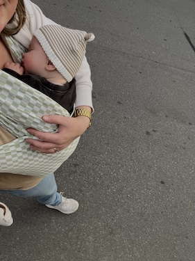 mother comfortably walking baby while using soft baby carrier received as a gift for new moms